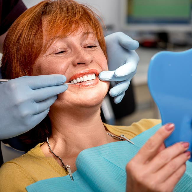 woman in dental chair smiling in mirror